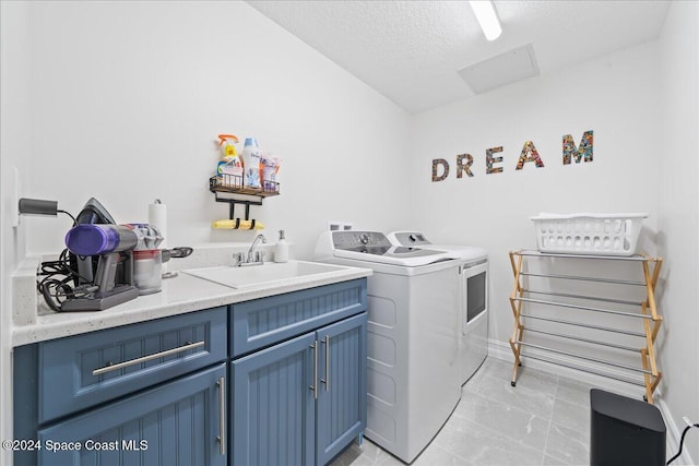 clothes washing area with cabinets, sink, washer and dryer, and a textured ceiling