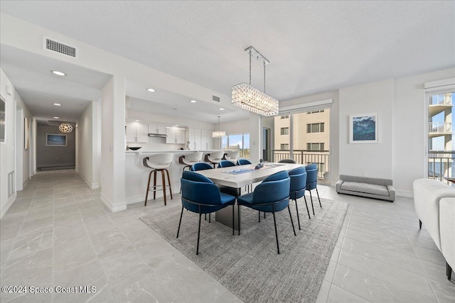 dining space with a chandelier and a textured ceiling