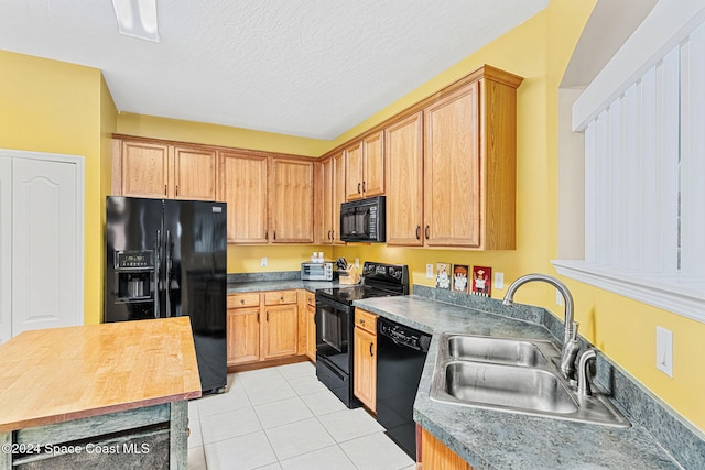 kitchen featuring a textured ceiling, light tile patterned flooring, sink, and black appliances