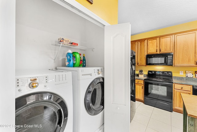 washroom featuring light tile patterned floors, a textured ceiling, and washer and clothes dryer