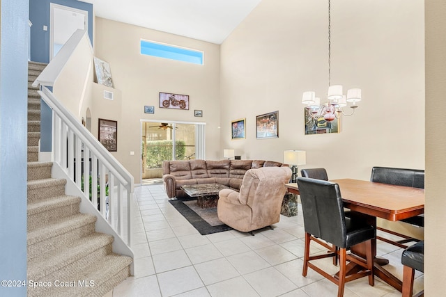 living room featuring light tile patterned floors, ceiling fan with notable chandelier, and a high ceiling