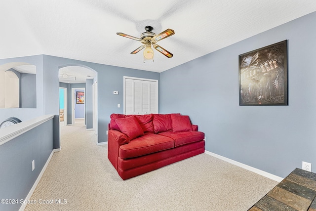 carpeted living room with a textured ceiling and ceiling fan