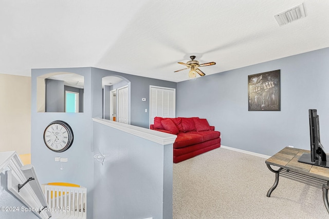 carpeted living room featuring ceiling fan and a textured ceiling