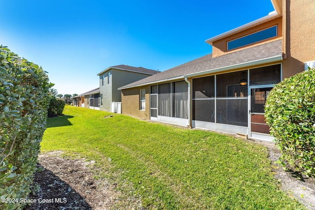 rear view of property featuring a yard and a sunroom