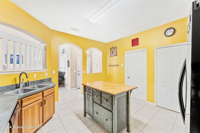 kitchen featuring dishwasher, sink, a textured ceiling, and light tile patterned flooring