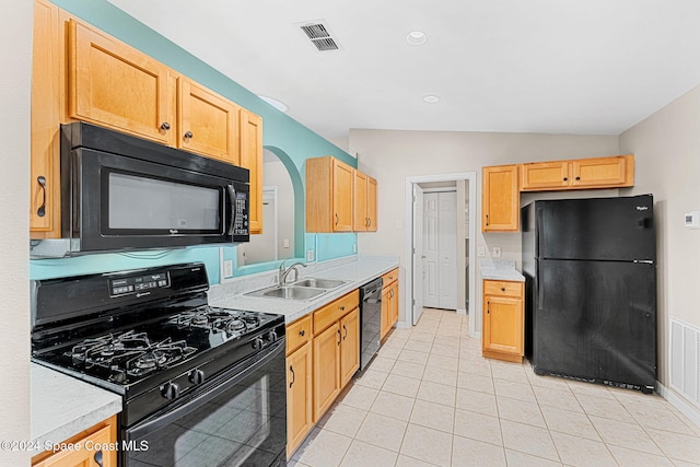 kitchen with light tile patterned floors, light brown cabinetry, vaulted ceiling, black appliances, and sink