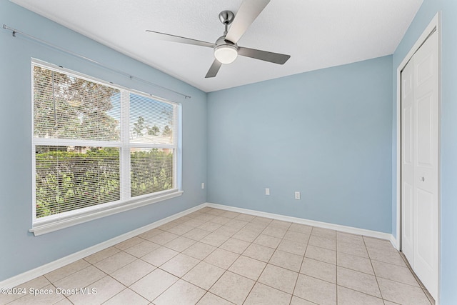 empty room with a textured ceiling, ceiling fan, and light tile patterned flooring