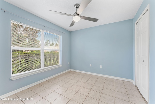 2122 Spring Creek Cir NE, Palm Bay, FL 32905 - unfurnished bedroom featuring a closet, ceiling fan, light tile patterned flooring, a textured ceiling, and baseboards