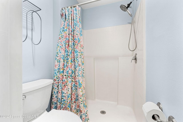 bathroom featuring toilet and curtained shower