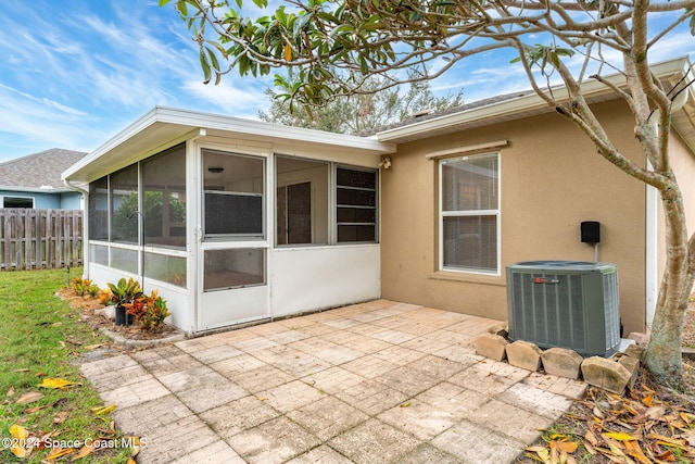 rear view of house featuring a patio area, a sunroom, and central AC