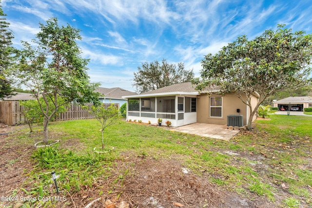 rear view of house featuring a lawn, central air condition unit, a patio, and a sunroom