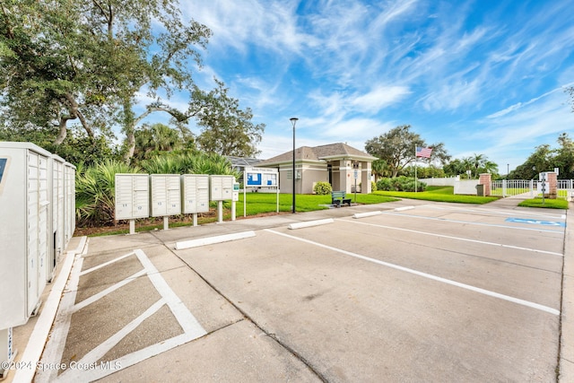 view of vehicle parking featuring mail boxes and a lawn