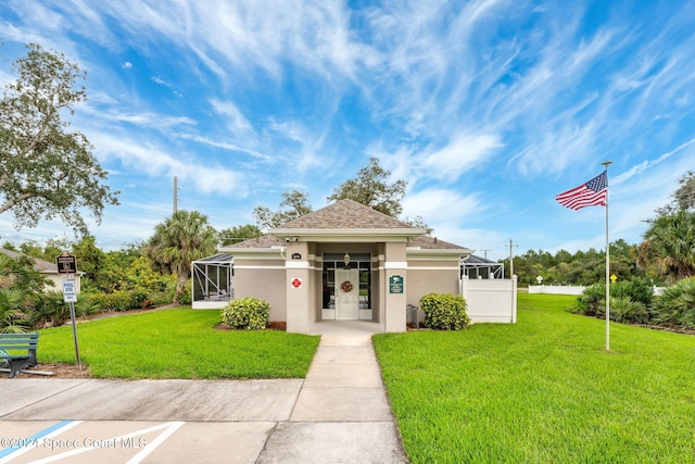 view of front of home featuring glass enclosure and a front lawn