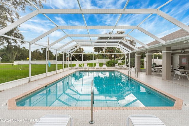 view of swimming pool featuring a yard, a patio area, and glass enclosure