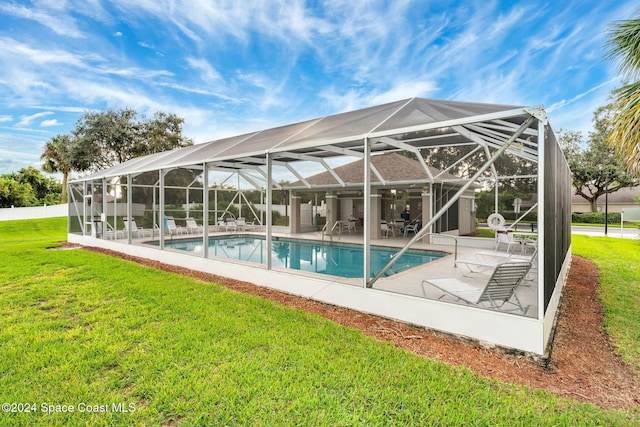 view of swimming pool featuring a lanai, a yard, and a patio