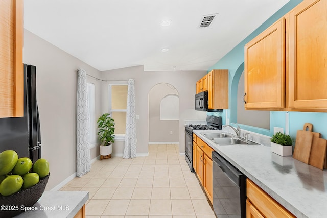 kitchen featuring black appliances, lofted ceiling, light brown cabinets, sink, and light tile patterned floors