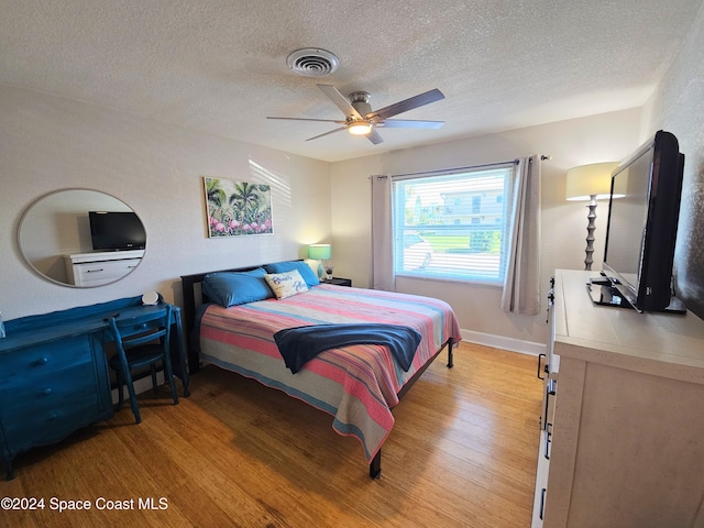 bedroom with ceiling fan, light hardwood / wood-style floors, and a textured ceiling