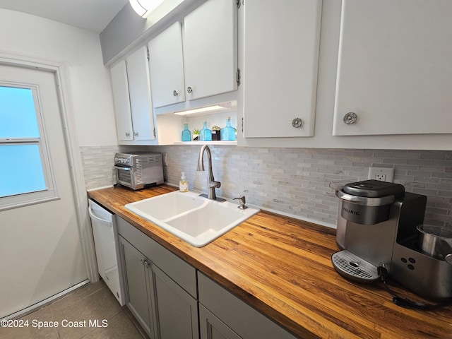 kitchen with white dishwasher, backsplash, sink, and wooden counters