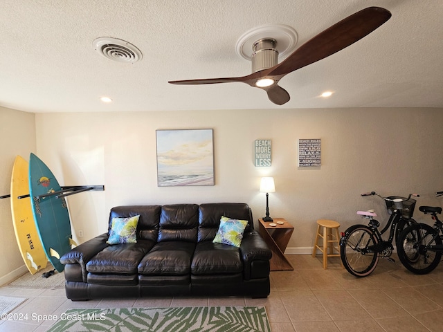 living room with tile patterned flooring, a textured ceiling, and ceiling fan