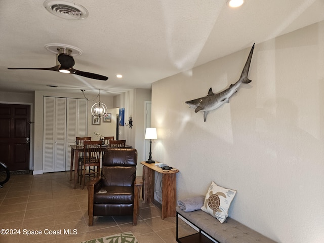 sitting room featuring tile patterned flooring and ceiling fan with notable chandelier