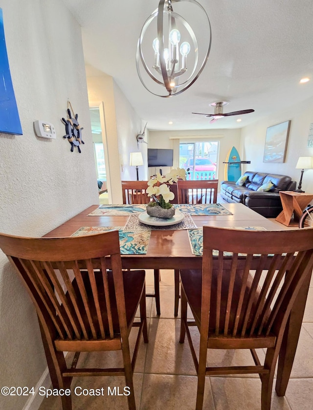 tiled dining space featuring ceiling fan with notable chandelier