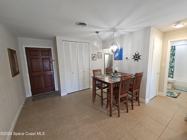 dining room with light tile patterned floors, a textured ceiling, and a notable chandelier