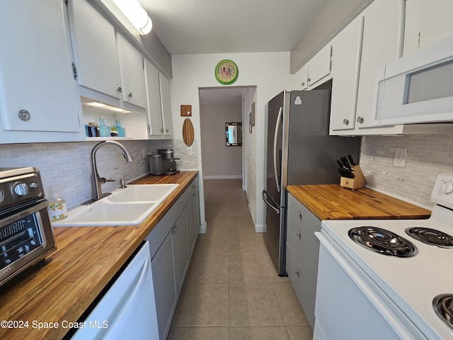 kitchen featuring light tile patterned floors, white appliances, white cabinetry, and sink