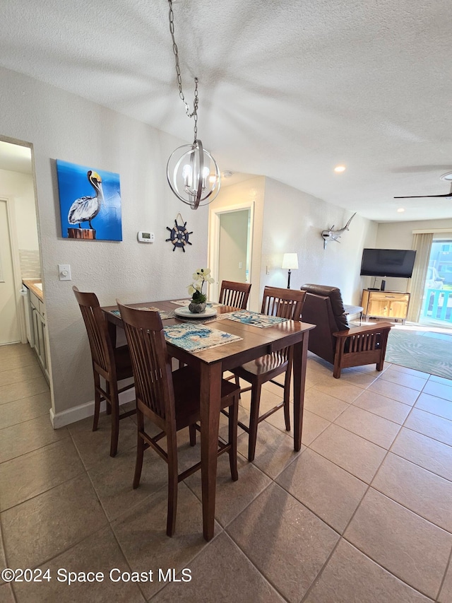 dining area featuring tile patterned flooring, a textured ceiling, and ceiling fan with notable chandelier