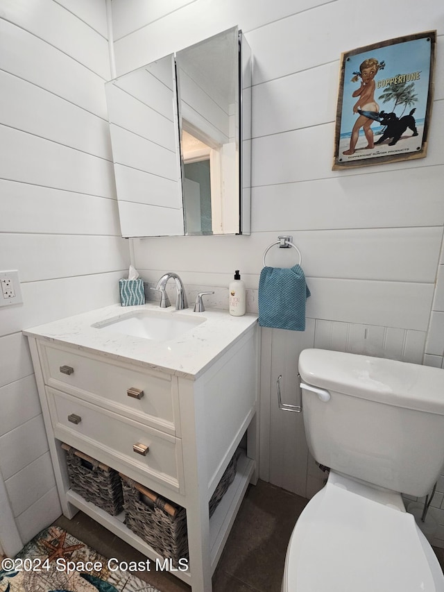 bathroom with wood walls, vanity, and toilet