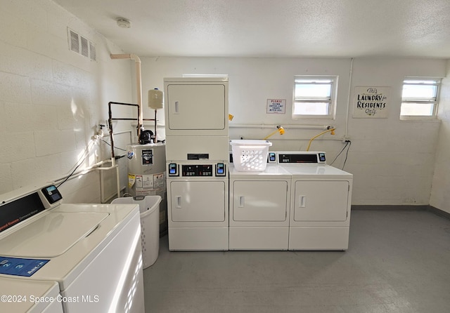 laundry area with gas water heater, separate washer and dryer, a textured ceiling, and stacked washer and clothes dryer