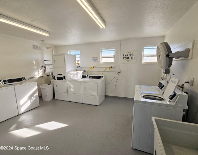 laundry room featuring sink, a textured ceiling, stacked washer / dryer, and washing machine and clothes dryer