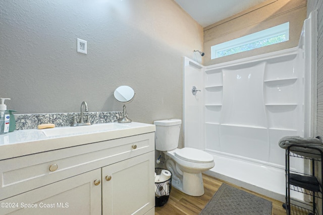 bathroom with a shower, vanity, hardwood / wood-style flooring, and toilet