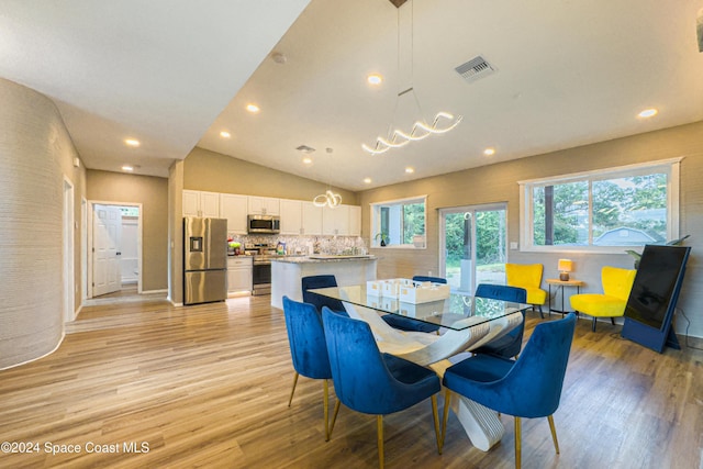 dining space featuring a notable chandelier, light wood-type flooring, and lofted ceiling