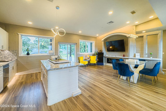 kitchen featuring pendant lighting, backsplash, white cabinets, light hardwood / wood-style floors, and a kitchen island