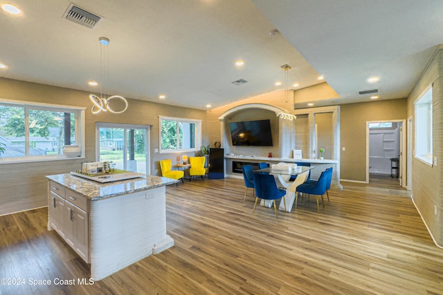 kitchen featuring light stone countertops, a kitchen island, pendant lighting, and light wood-type flooring