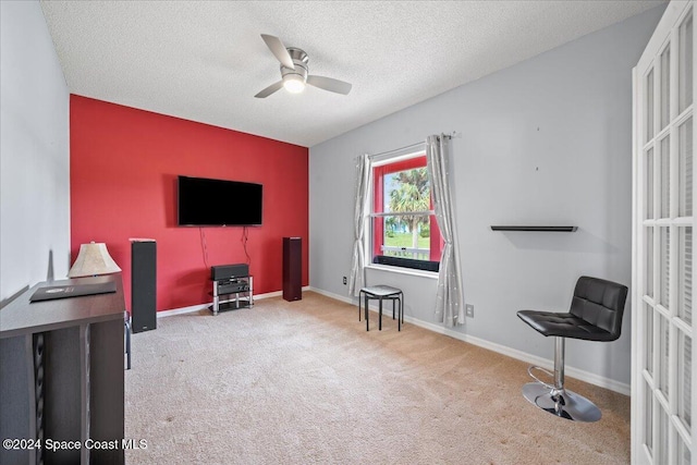 sitting room featuring ceiling fan, light colored carpet, and a textured ceiling