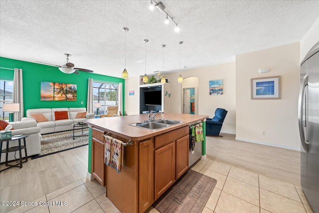 kitchen featuring a kitchen island with sink, sink, hanging light fixtures, a textured ceiling, and light hardwood / wood-style floors