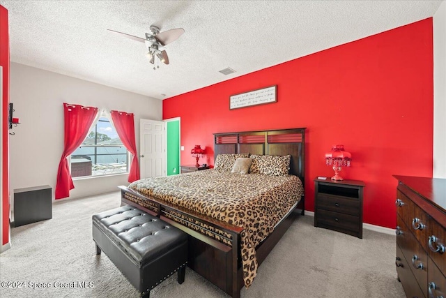 bedroom featuring ceiling fan, light carpet, and a textured ceiling