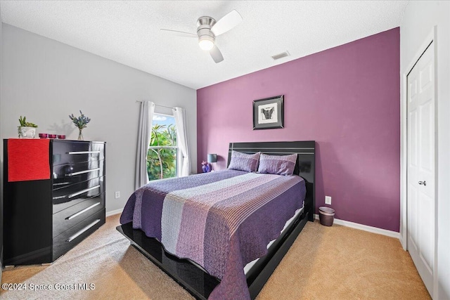 bedroom featuring light carpet, a textured ceiling, and ceiling fan