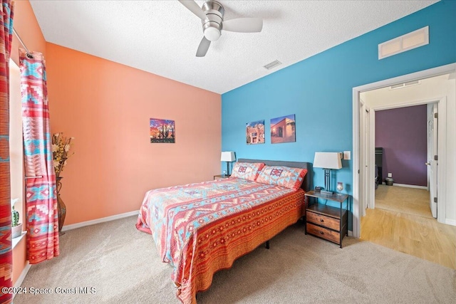 bedroom with ceiling fan, carpet floors, and a textured ceiling