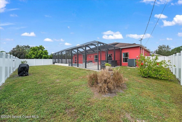 view of yard with a lanai, central air condition unit, and a patio