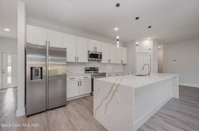 kitchen with sink, white cabinetry, stainless steel appliances, and a kitchen island with sink