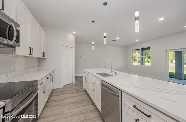 kitchen featuring white cabinetry, sink, stainless steel appliances, light hardwood / wood-style flooring, and decorative light fixtures