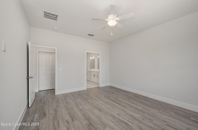 unfurnished bedroom with ceiling fan, light hardwood / wood-style flooring, ensuite bathroom, and a textured ceiling