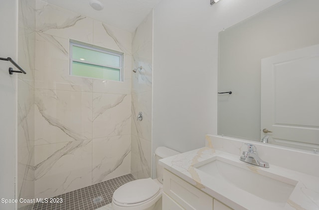 bathroom with a tile shower, vanity, and toilet