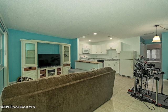 living room featuring a textured ceiling, light tile patterned flooring, and sink