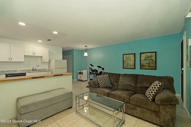 living room featuring sink, light tile patterned floors, and a textured ceiling