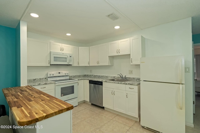 kitchen featuring butcher block counters, white appliances, sink, light tile patterned floors, and white cabinetry