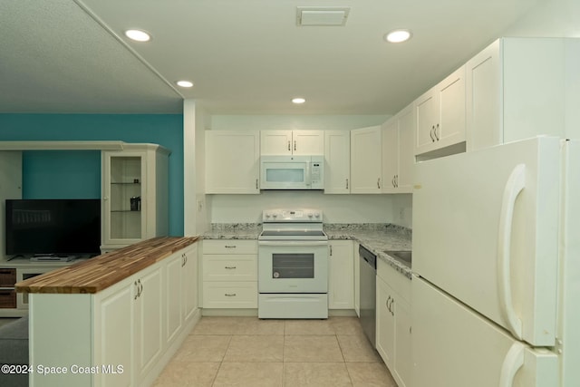 kitchen with light stone countertops, light tile patterned floors, white appliances, and white cabinetry