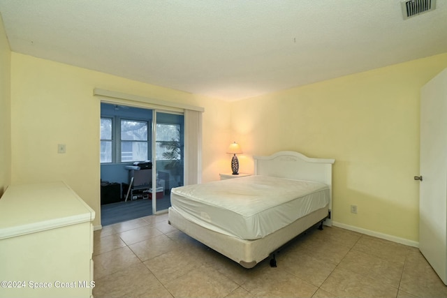 bedroom with light tile patterned flooring, access to exterior, and a textured ceiling